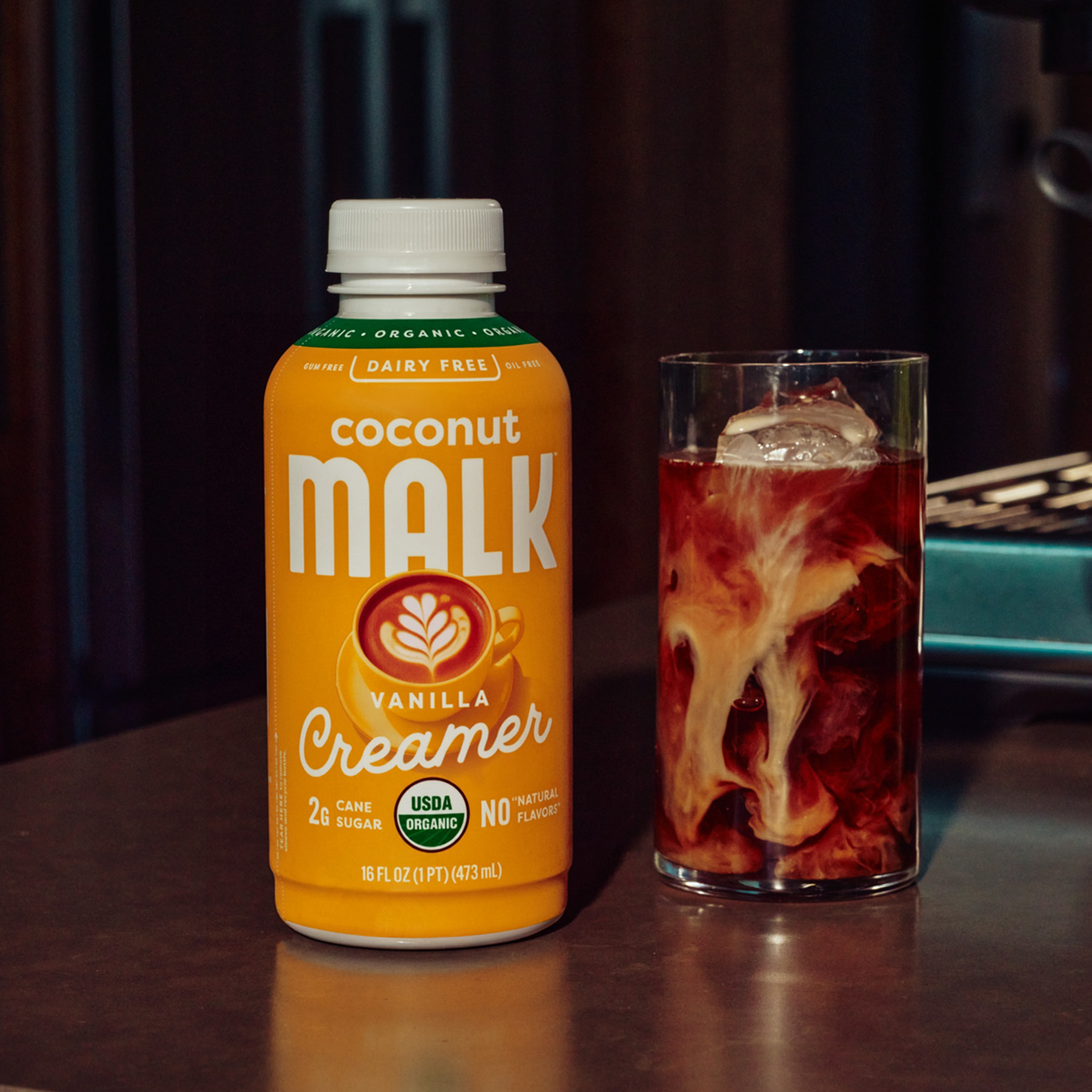 MALK Organic Non-Dairy Vanilla Coconut Milk Creamer bottle next to iced coffee