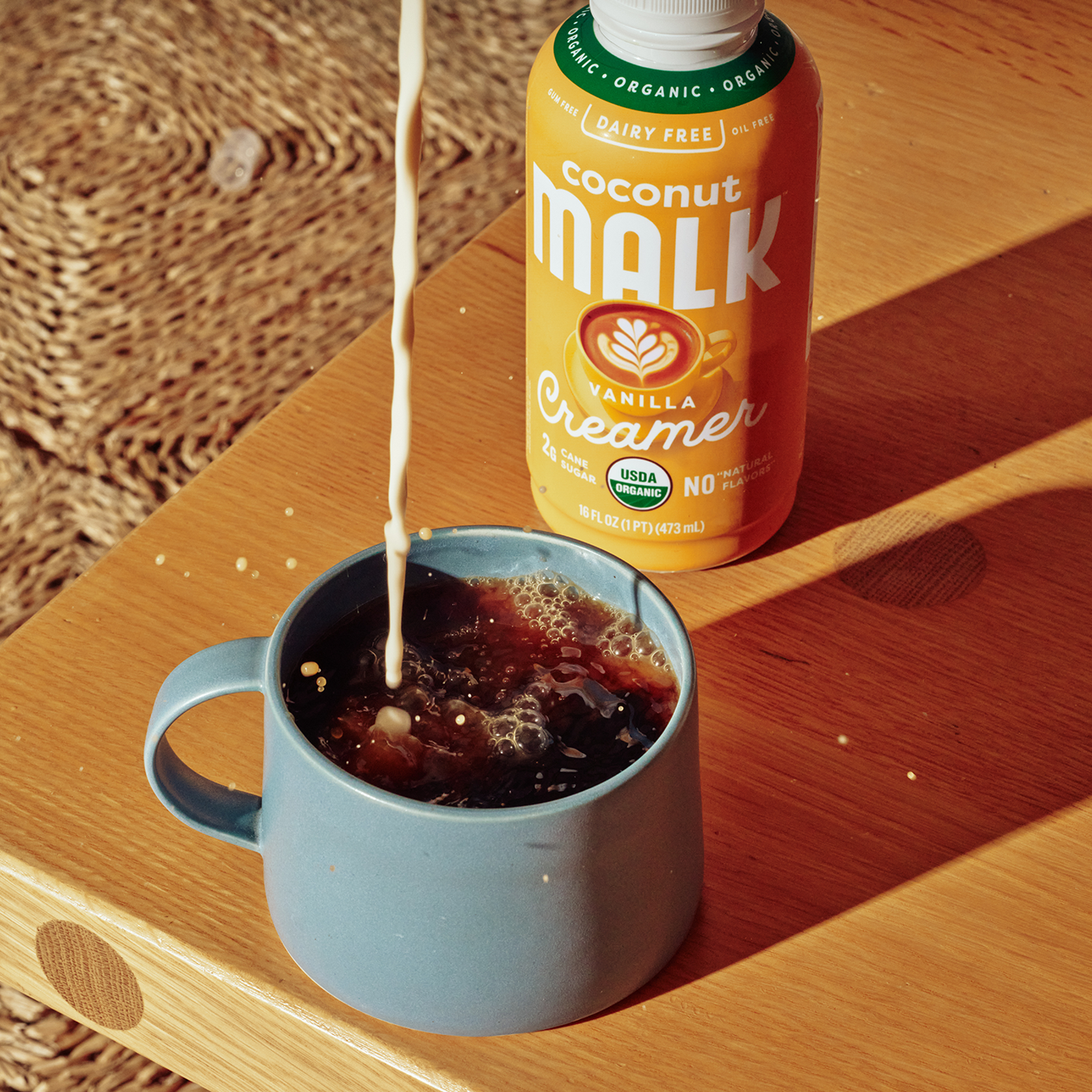MALK Vanilla Coconut Milk Creamer being poured into a cup of coffee.