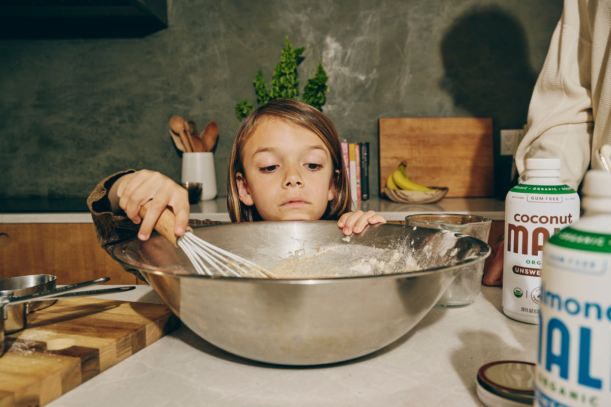 Child whisking a bowl of flour and other ingredients with MALK