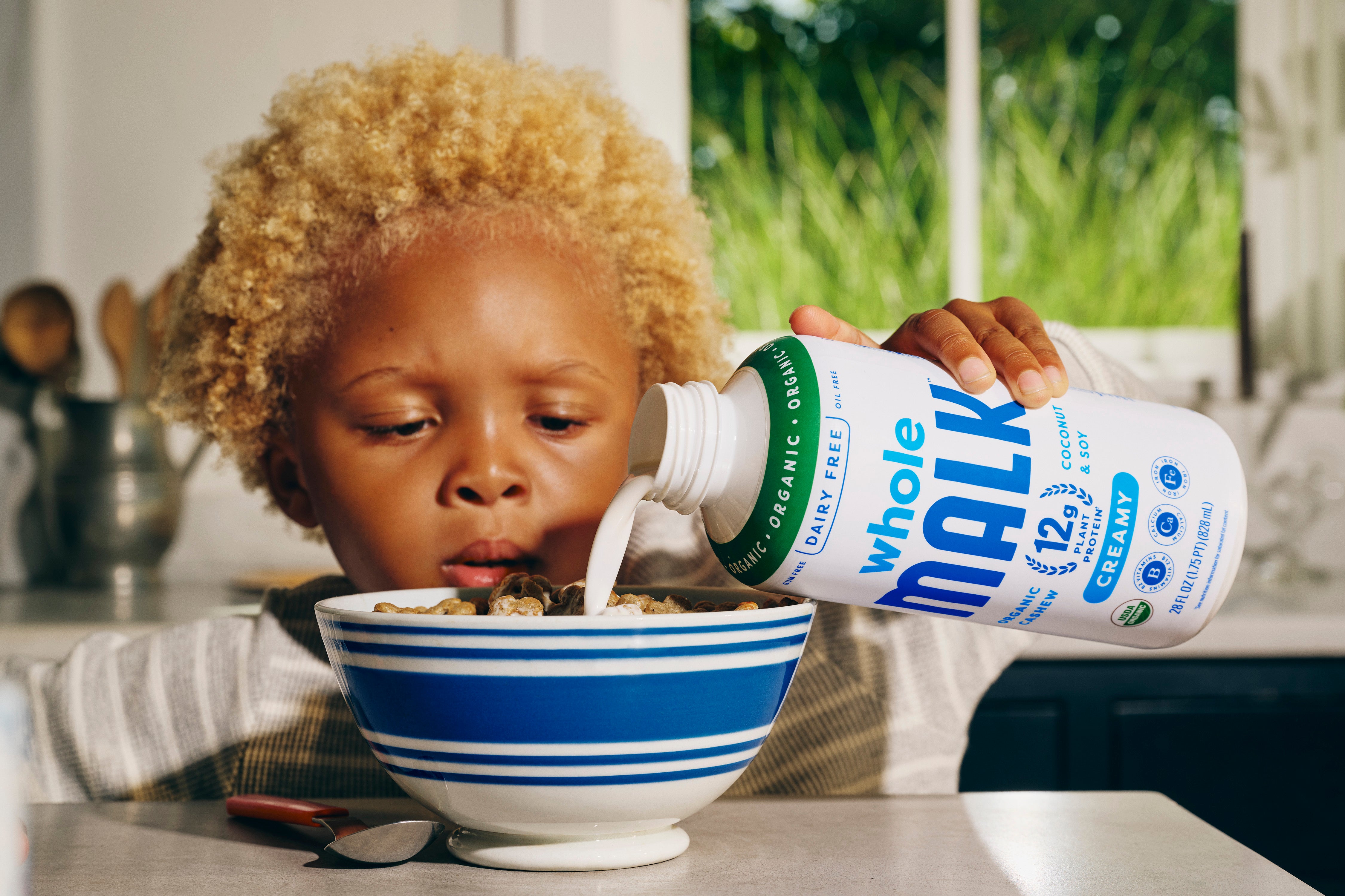 Child pouring a bottle of Whole MALK into a bowl of cereal