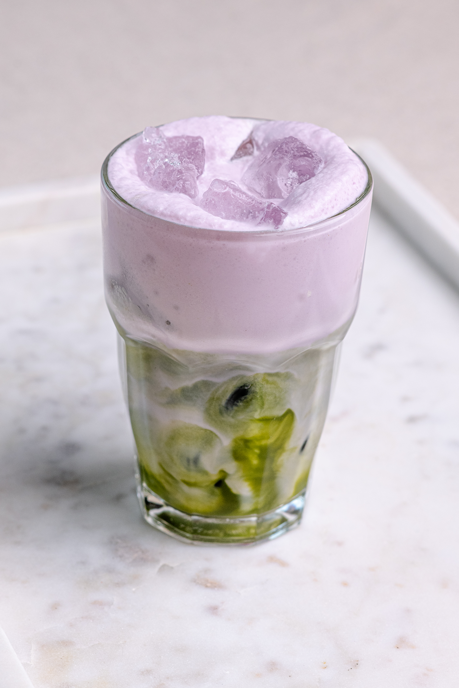 Iced lavender matcha latte with MALK Vanilla Almond Milk, layered with creamy green matcha and purple lavender foam over ice.