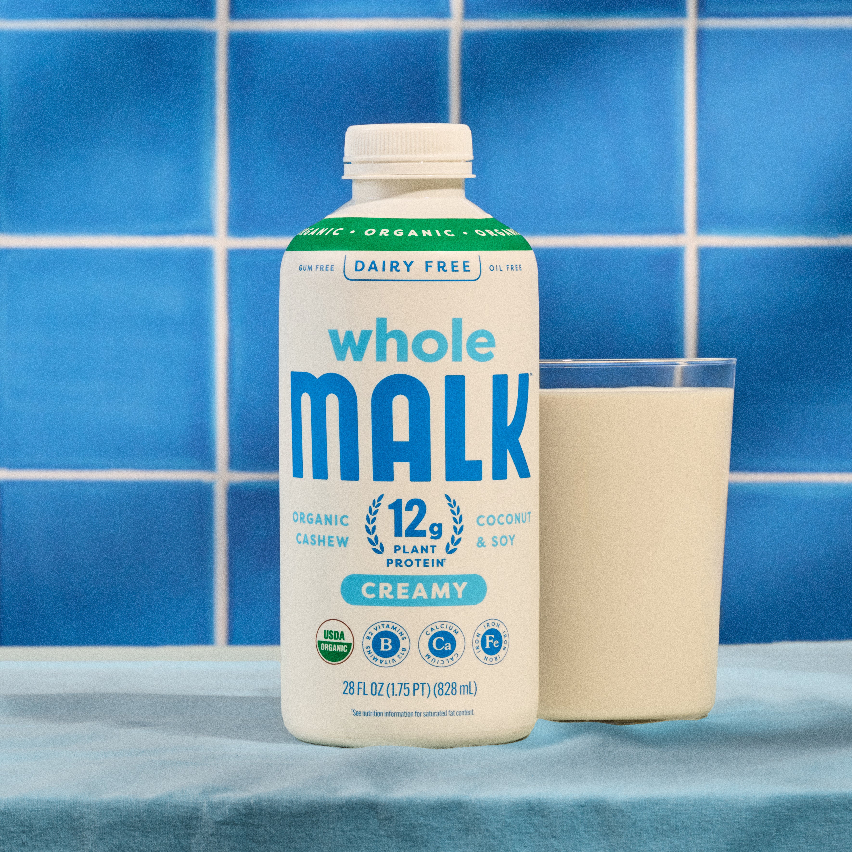 Whole MALK bottle next to a glass of Whole MALK with a blue tile backround
