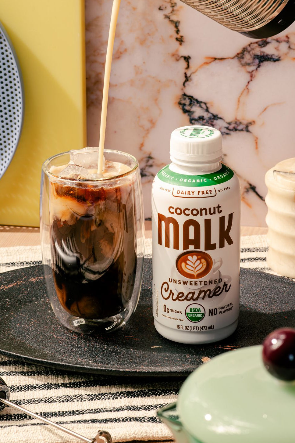 MALK Organic Unsweetened Coconut Creamer poured into iced cold brew to make a salted caramel cream coffee.