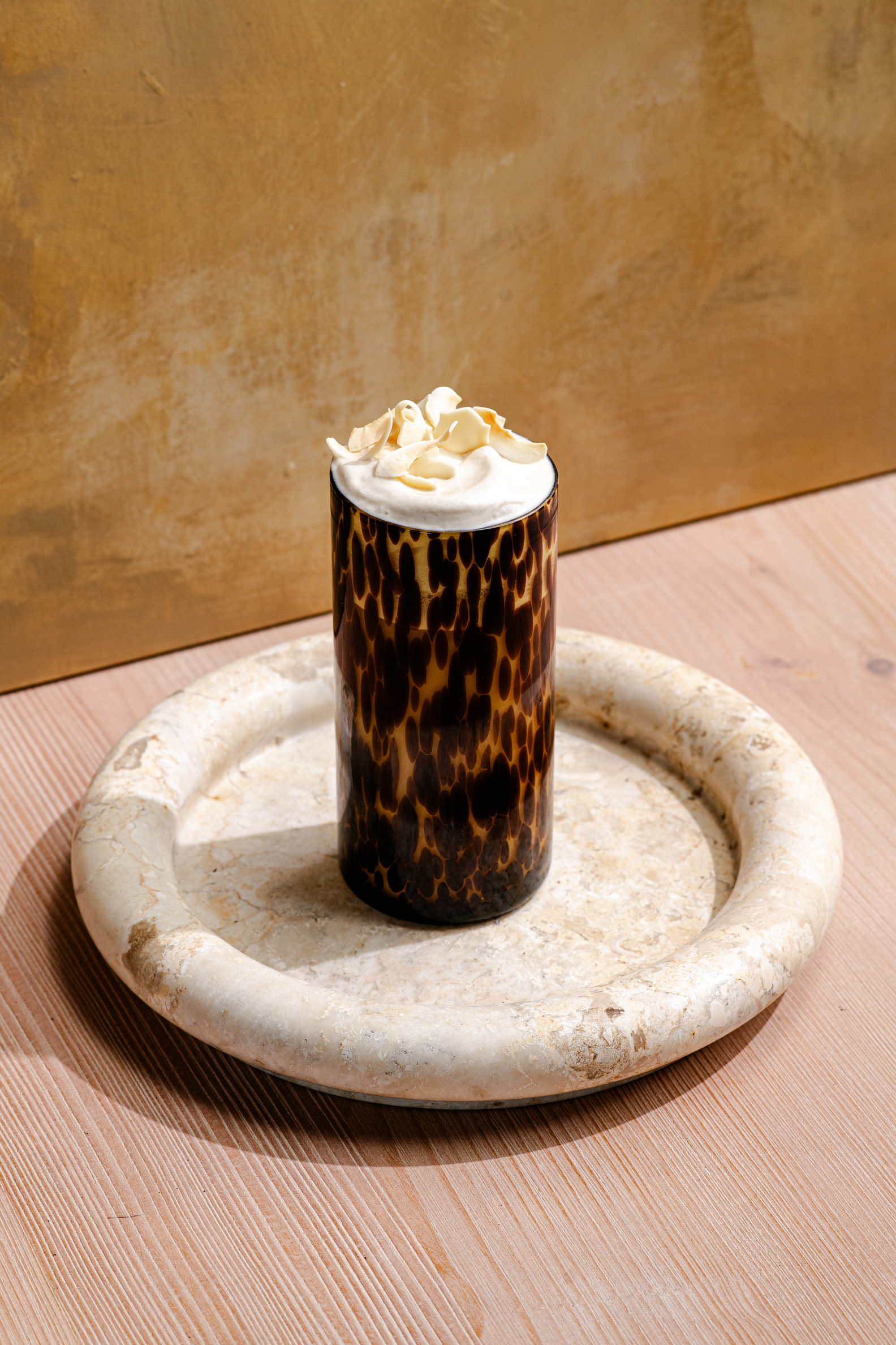 Iced sweet cream macchiato made with MALK Sweet Cream Coconut Creamer, layered with espresso and topped with coconut cold foam and toasted coconut flakes