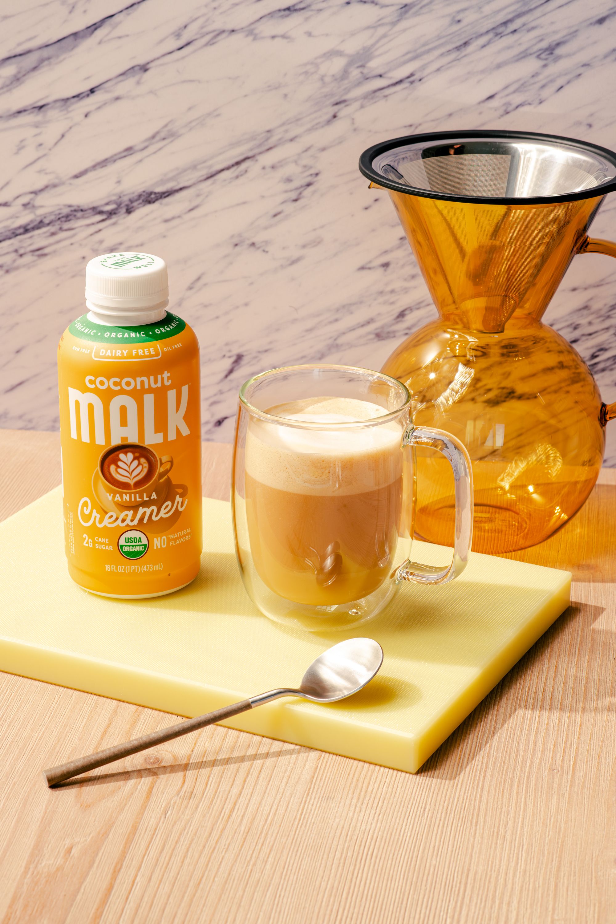 Creamy vanilla latte made with MALK Organic Vanilla Coconut Creamer, served with espresso in a glass mug.