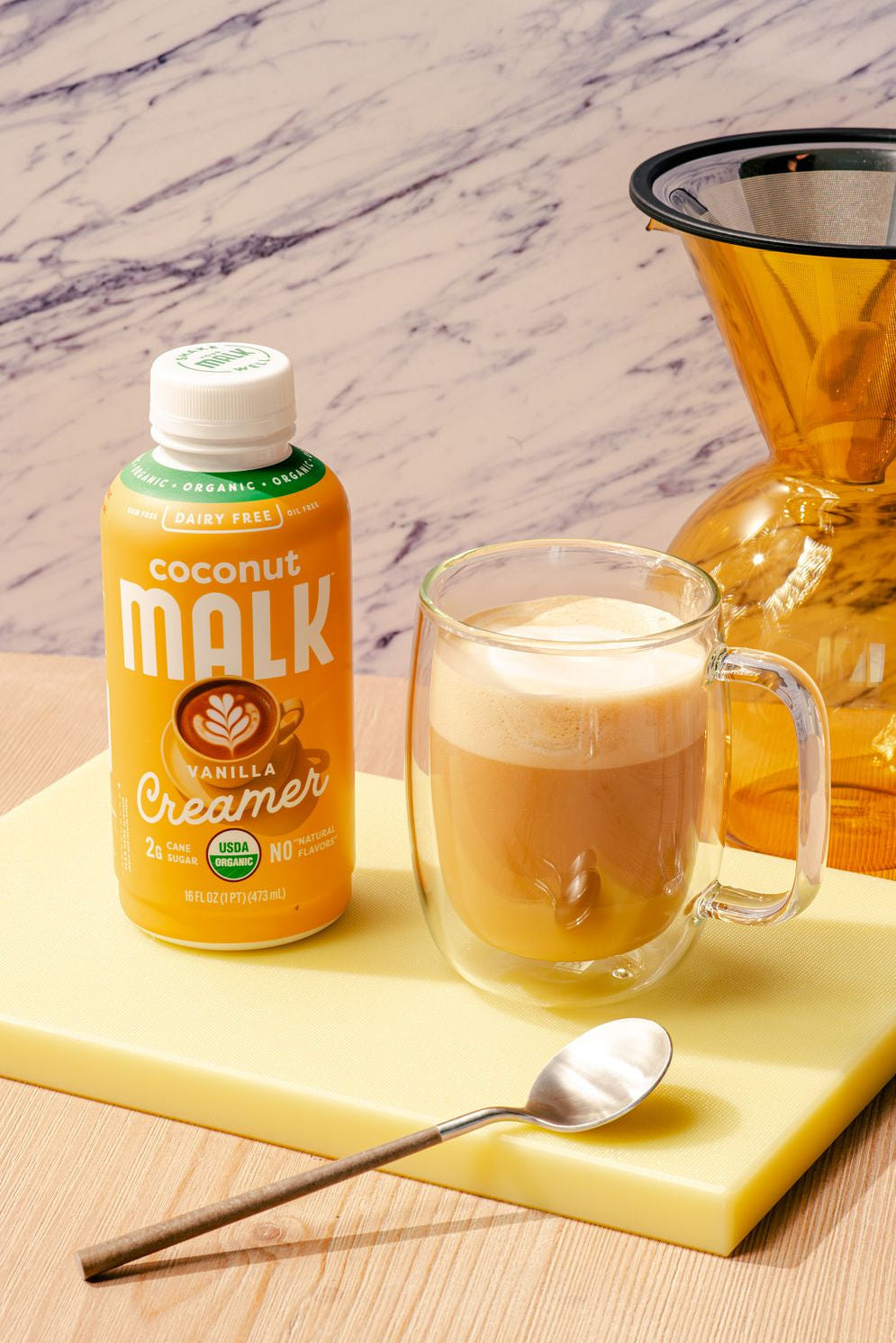 MALK Organic Vanilla Coconut Creamer next to a dairy-free vanilla latte with espresso and frothy coconut milk.