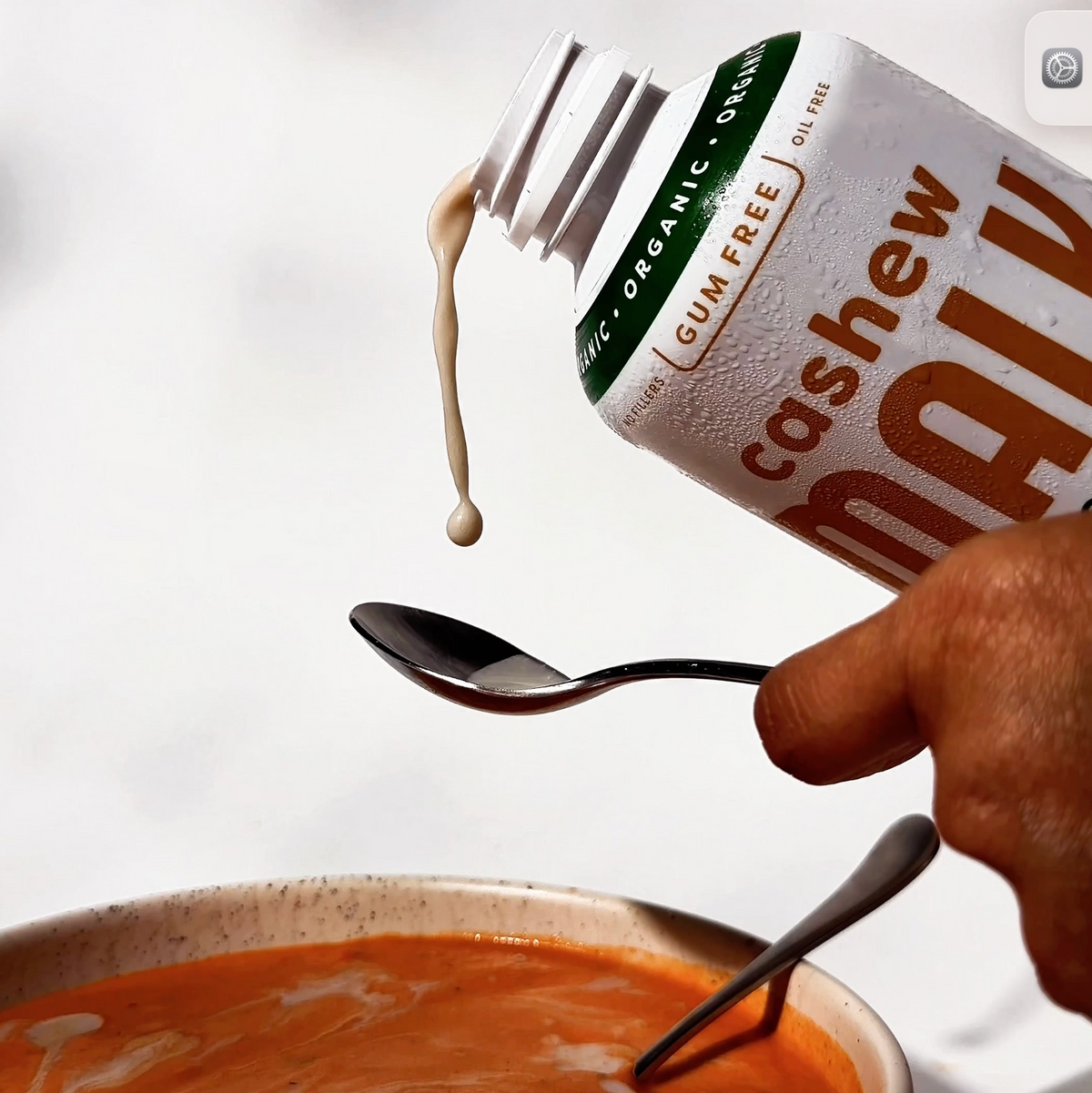 MALK Unsweetened Cashew Milk being poured into a bowl of tomato bisque