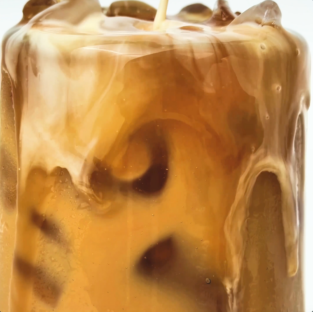 MALK Unsweetened Coconut Milk Creamer being poured into a glass of iced coffee