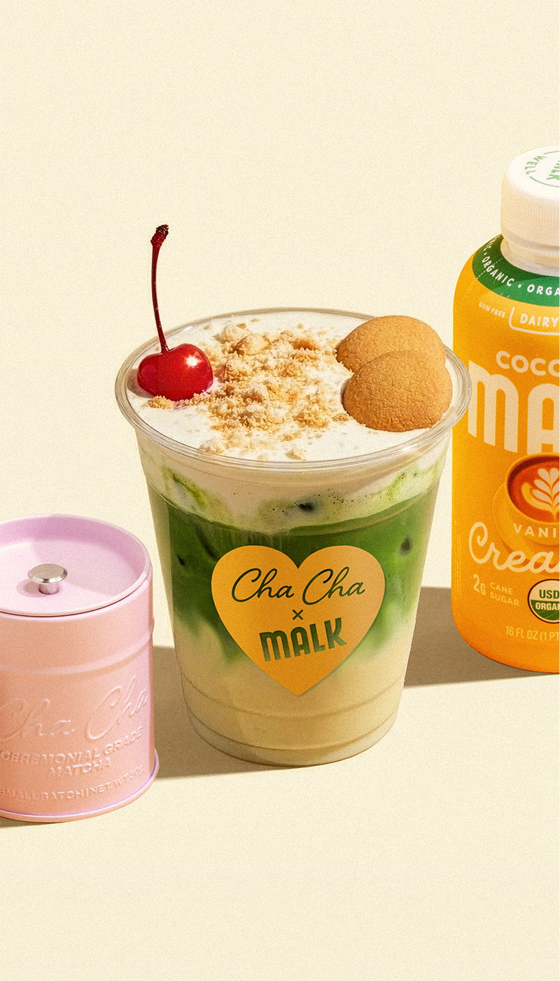 Banana cream matcha latte made with MALK coconut creamers, Cha Cha Matcha's Signature powder, topped with cold foam, wafer cookies, and a cherry.