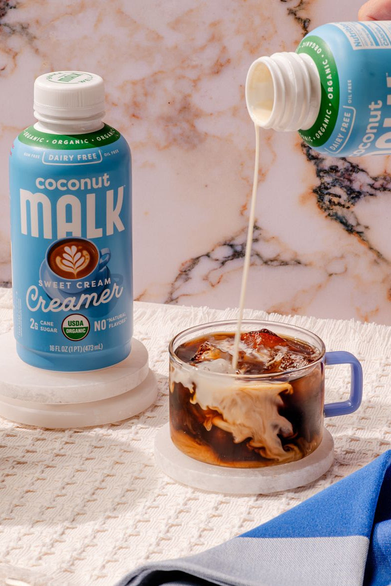 MALK Sweet Cream Coconut Creamer poured into a glass of iced cold brew coffee.