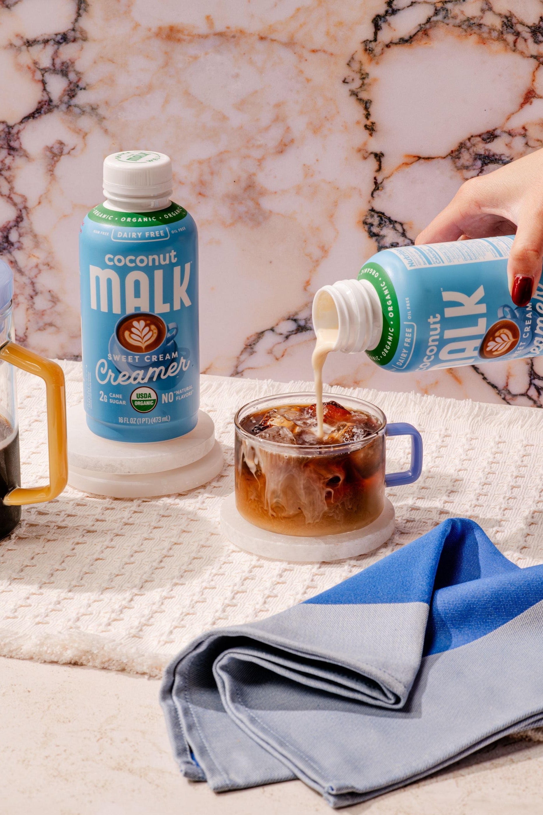 MALK Sweet Cream Coconut Creamer poured into a glass of iced cold brew coffee.