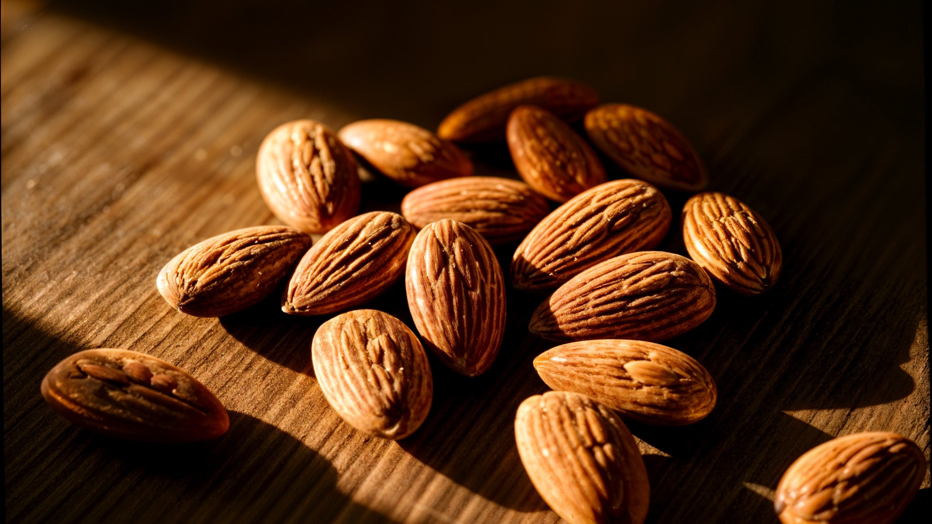 Almonds in a moody dark setting with natural light on a wooden surface