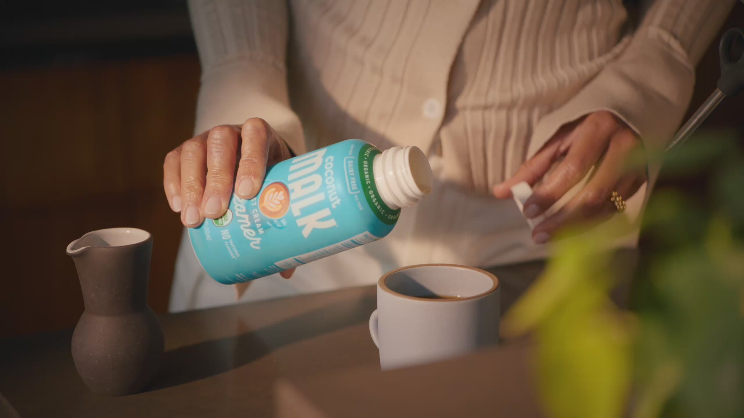 Video of MALK Sweet Cream Creamer being poured into mug. MALK Vanilla Coconut Creamer next to cup of matcha. Unsweetened Creamer lid being unscrewed. People happy, enjoying their beverages and the process of making their morning cup. 